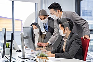 Group of Asian young business people working on computer in office with new normal lifestyle. Man and woman wear protective face m