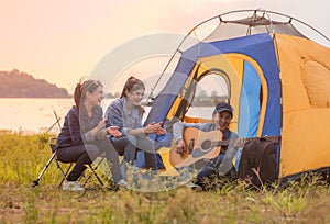 Group of Asian young woman friends having fun and enjoy in music of guitar on parks and outdoor camping