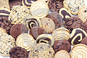 A group of assorted cookies. Chocolate chip, oatmeal, raisin, Danish cookies and biscuits in the shape of a spiral pattern close-u