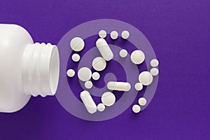 Group of assorted white tablets. Capsules spilling out of white