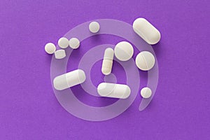 Group of assorted white tablets. Violet background.