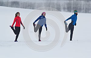 Group of athletes warming up and stretching before exercise in winter forest