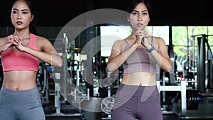 Group of athletic young Asian people in sportswear doing squat and exercising at the gym