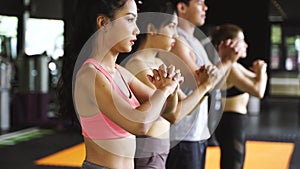 Group of athletic young Asian people in sportswear doing squat and exercising at the gym. Intense workout and healthy