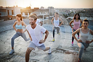 Group of athletic young people, friends in sportswear doing exercises. Sport outdoors