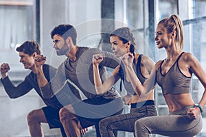 Group of athletic young people in sportswear doing lunge exercise at the gym