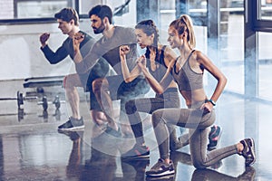 Group of athletic young people in sportswear doing lunge exercise at the gym