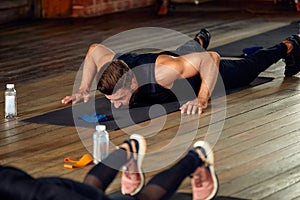 group of athletic young people in sportswear doing push ups or plank at the gym, group fitness concept