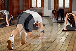 group of athletic young people in sportswear doing push ups or plank at the gym, group fitness concept