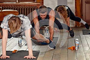 group of athletic young people in sportswear doing push ups or plank at the gym, group fitness concept