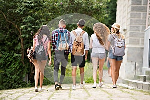 Group of attractive teenage students walking from university.