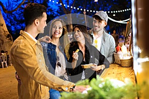 Group of attractive young friends speaking and visiting eat market in the street.