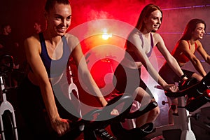 group of attractive young women at the gym riding on spinning bike