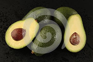 Group of avocado with half on black background