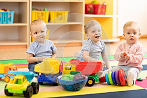 Group of babies is playing on floor in nursery. Children in the day care center. Fun in the children`s playroom