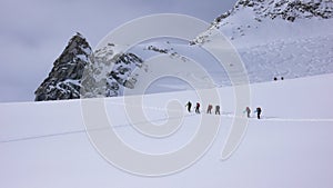 A group of backcountry skiers hike and climb to a remote moutain peak in Switzerland