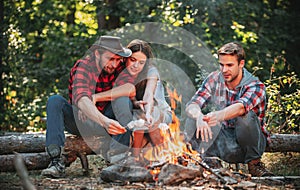 Group of backpackers relaxing near campfire. Friends spend leisure weekend forest nature background. Tourists relaxing