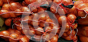 A group of bagged yellow onions stacked up in a pile