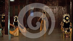 a group of Balinese dancers in yellow shawls dance slowly with their friends