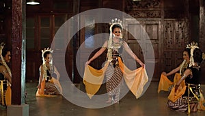 a group of Balinese dancers in yellow shawls dance slowly with their friends