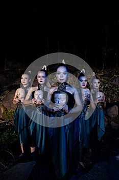 A Group of Balinese woman line up with the wooden mask in their hands while wearing a traditional dance costumes