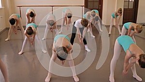 Group of ballet girls doing stretching exercises before dance lessons.