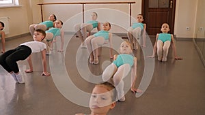 Group of ballet girls doing stretching exercises before dance lessons.