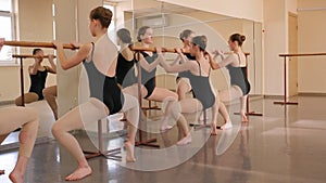 Group of ballet girls doing stretching exercises before dance lessons.
