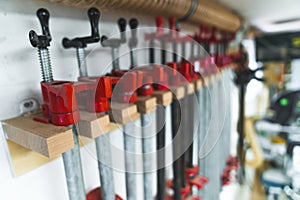 Group of bar clamps used in woodworking for glueing pieces together. Carpenter studio interior. Closeup indoor shot.