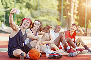 Group of basketball players taking selfie together after training at outdoor arena, copy space