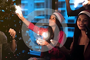 Group of beautiful young people in Santa hats having fun with sparklers.