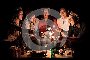 Group of beautiful young people in Santa hats having fun with sparklers.