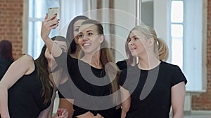 Group of beautiful young women taking a selfie during a break on a pole fitness class