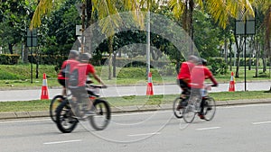 Group of bikers ride along city road, four men on bicycles ride down street
