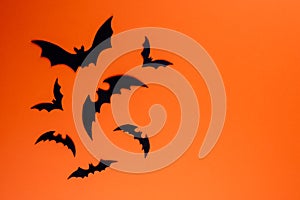 Group of black paper bats on orange background