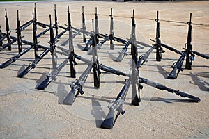 The group of black rifles lay on the cement floor to organize military combat concepts.