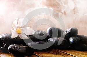 Group of black stones on wood base with steam background