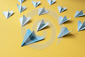 Group of blue paper aeroplane origami on yellow background