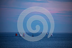 Group of boats and yachts in the sea with sails during dusk