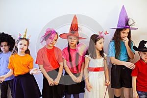 Group of borred kids on a birthday party. Children in funny costumes and hats having bad moods photo