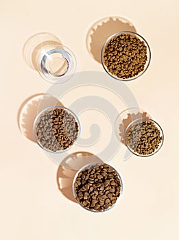 A group of bowls with different types of dry food on the table. Beige background