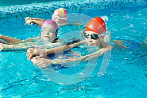 Group of boys and girls train and learn to swim in the pool with an instructor. Development of children's sports