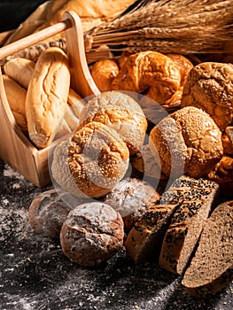 A group of bread on the black wooden table with sunlight