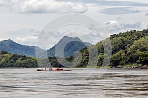 Group of Buddhist monks navigate the Mekong River with a long tail boat in Luang Prabang, Laos