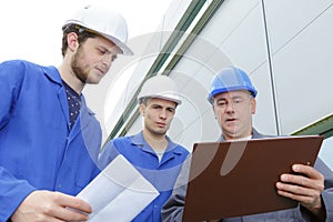 Group builders in hardhats with clipboard outdoors