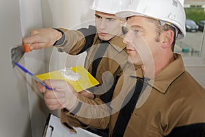 Group builders in hardhats with plastering tools indoors