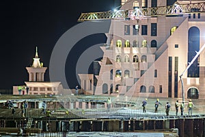 Group of building workers working on illuminated construction site at night