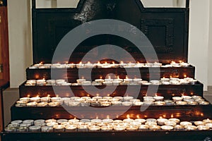 Group of burning candles on church altar close-up in christian catholic church, flaming candles, funeral, faith and memory concept