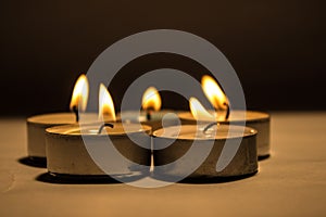 Group of burning small candles on a black background.