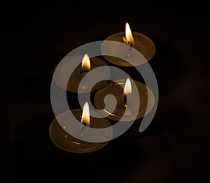 Group of burning small candles on a black background.